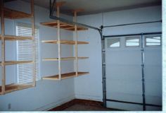 an empty room with some shelves in the corner and a garage door open to reveal another room