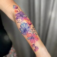 a woman's arm with watercolor flowers on the left side of her arm