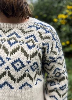 the back of a woman's sweater with blue, green and white designs on it