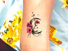 a woman's arm with a flowered tattoo on the left side of her wrist