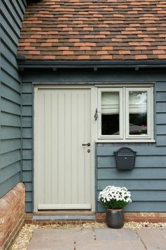 a blue house with a white door and flower pot on the front step next to it