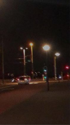 a person standing on the side of a road at night with street lights in the background