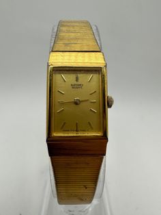 For sale is a vintage Seiko 1F20 ladies' gold-tone tank dress watch, featuring a classic rectangular-square design with a minimalist style. Made in Japan, this small and dainty timepiece is perfect as a thoughtful gift for her, mom, or any woman who appreciates timeless fashion. The watch has a new battery and runs great. Please note, there are some scratches on the face and some of the plating on the strap is worn, adding to its vintage character. Please check wrist size before purchasing. A st Square Fashion, Thoughtful Gifts For Her, Watch Gift, Vintage Character, Dress Watch, Watch Gifts, Square Design, Tank Dress, Minimalist Fashion