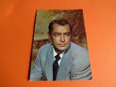 an old photo of a man in a suit and tie on a orange background,