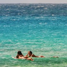 two people laying on surfboards in the ocean