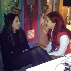 two young women sitting next to each other in front of lockers with decorations on them