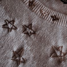 some brown stars on a white sweater and a black object in the background with words written across it