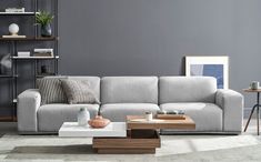 a modern living room with grey walls and white carpeted flooring, large sectional sofa in the center