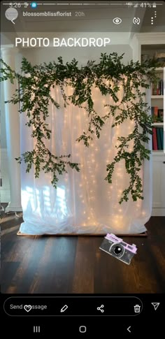 the photo backdrop is decorated with greenery and fairy lights