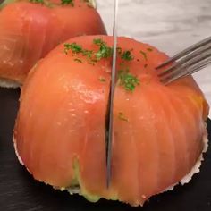 two pieces of salmon being cut with a pair of tongs on top of them