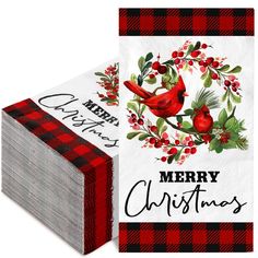 a christmas card with a cardinal on it and holly wreath around the neck, sitting next to a stack of red plaid napkins