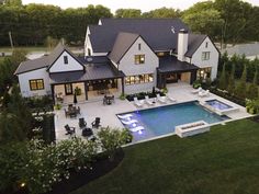 an aerial view of a house with a swimming pool in the foreground and landscaping around it