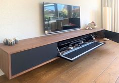 a flat screen tv sitting on top of a wooden entertainment center next to a window