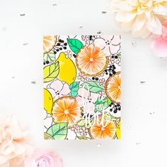 a card with flowers on it next to some pink and yellow flowers in the background