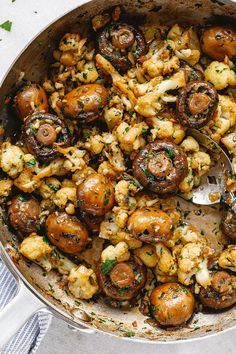 a skillet filled with mushrooms and other vegetables on top of a white table cloth