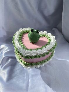 a cake shaped like a heart with a frog on top