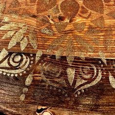 a piece of wood with gold paint and designs on the top, sitting next to a pair of shoes