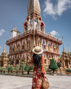 a woman wearing a hat standing in front of a building with gold and red trim