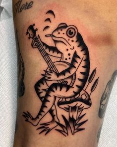 a black and white photo of a lizard with a guitar tattoo on his leg,