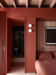 a bedroom with red walls and two lamps on the wall next to a pink bed