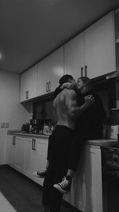 black and white photograph of two people embracing each other in the middle of a kitchen