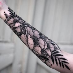 a woman's arm with black and white flowers on the inside of her arm