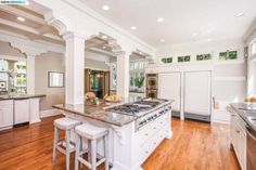 a large kitchen with white cabinets and wooden floors