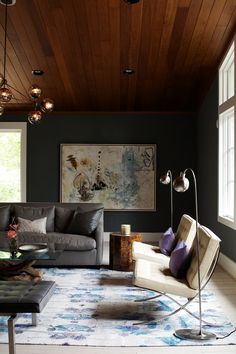 a living room filled with furniture and a large painting on the wall above it's windows