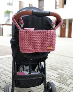 a baby stroller with a pink knitted basket on it's handlebars