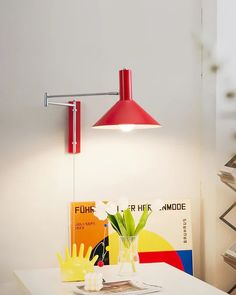 a red lamp is on the wall above a white table