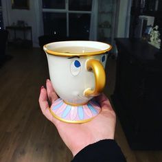 a hand holding a beauty and the beast coffee cup