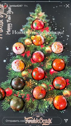 a christmas tree made out of marbles on top of a black board with the words happy holidays written above it