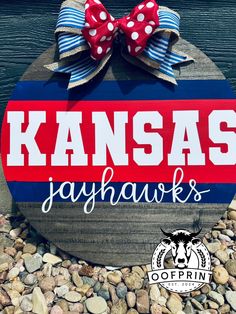 a wooden sign that says kansas jayhawk's with a red, white and blue bow on it