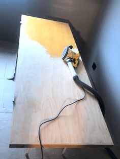 a corded sanding machine on top of a wooden table in the process of being sanded