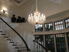 a chandelier hanging from the ceiling in a room with white walls and windows