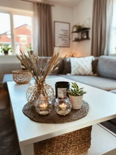 a living room filled with furniture and plants on top of a table in front of a window