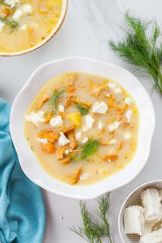 two bowls filled with soup on top of a white table next to blue napkins