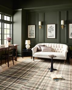 a living room with green walls and furniture in the corner, including a white couch