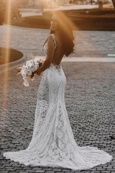 a woman in a wedding dress standing on a brick road with her back to the camera