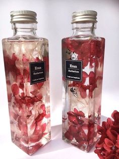 two glass bottles with red flowers in them