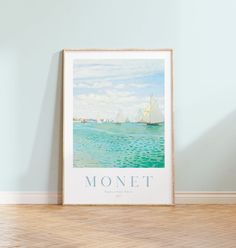 there is a framed poster on the wall next to a wooden floor with a sailboat in the water