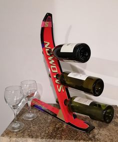 two wine glasses are sitting on a counter next to a rack with three bottles of wine