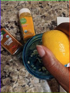 a person holding an orange in their hand next to some other items on the counter