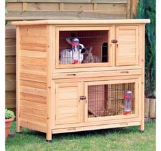 an outdoor rabbit hut with two rabbits in it's doors and one on the outside