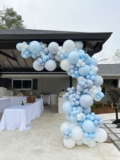 blue and white balloons are attached to the top of a balloon arch at a party