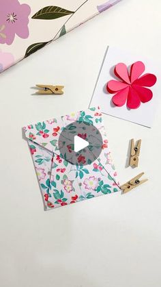 some paper flowers and clothes pins on top of a white table with scissors, clippings and other items