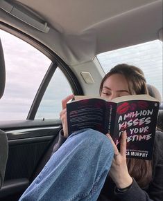 a woman sitting in the back seat of a car reading a book