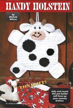 a crocheted cow ornament hanging on a wooden wall next to other items