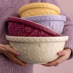 a woman is holding four bowls in her hands, each with different designs on them