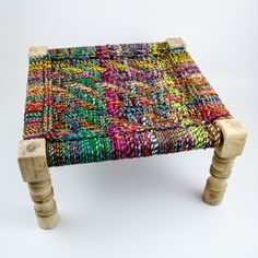 a multicolored stool with wooden legs on a white background